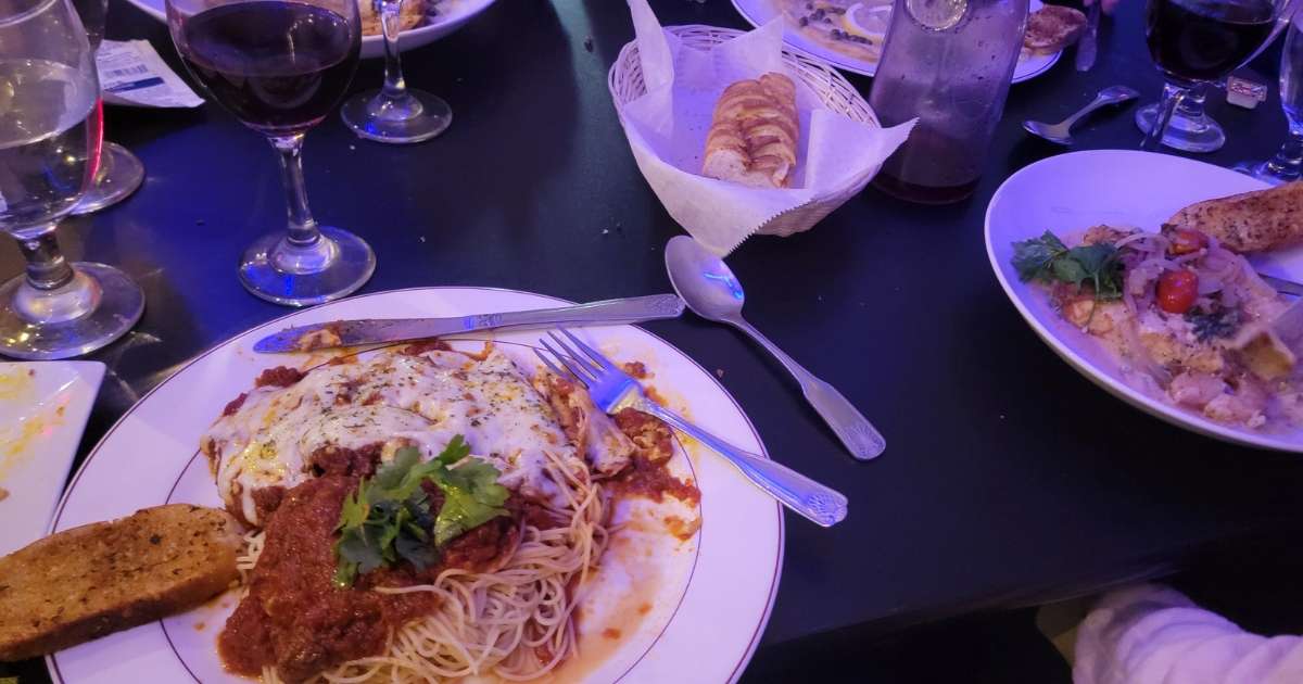 A table with plates of chicken parmesan and pasta and bread at La Dolce Vita