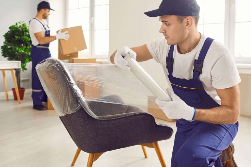 A crew of Millsboro movers packing boxes and putting plastic wrap on a chair