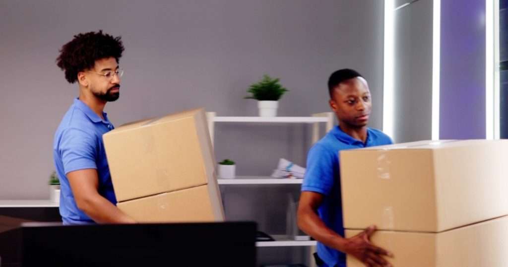 Two Milford Delaware movers relocating packed boxes amid an office move.