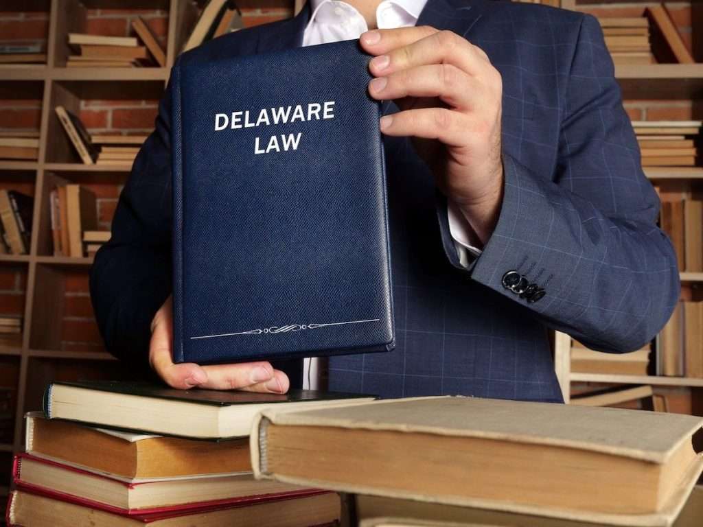A lawyer in a blue suit holding up a book that says Delaware Law