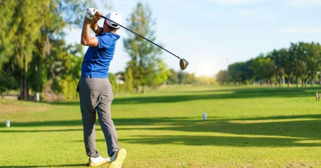 Golfer swinging on a sunny course near Bridgeville, DE, surrounded by lush green fairways and trees.