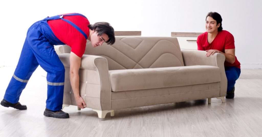 Two furniture movers from a Riverview moving company placing a couch in a room