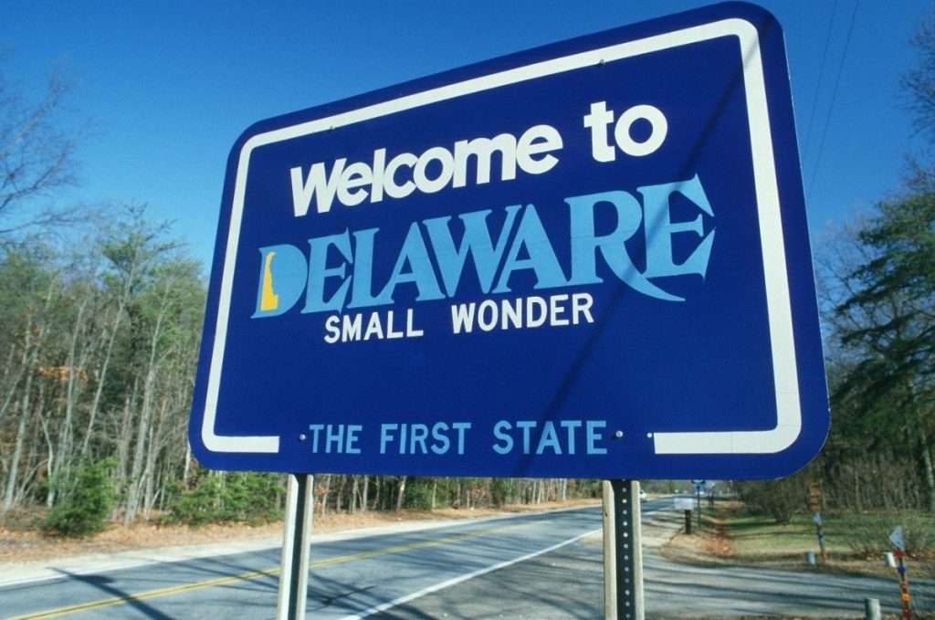 A sign on the highway that says “welcome to Delaware, small wonder, the first state” 